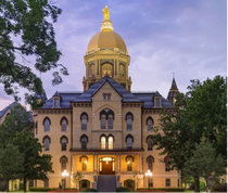 Notre Dame campus building with the Basilica Dome in the background  on at dusk 